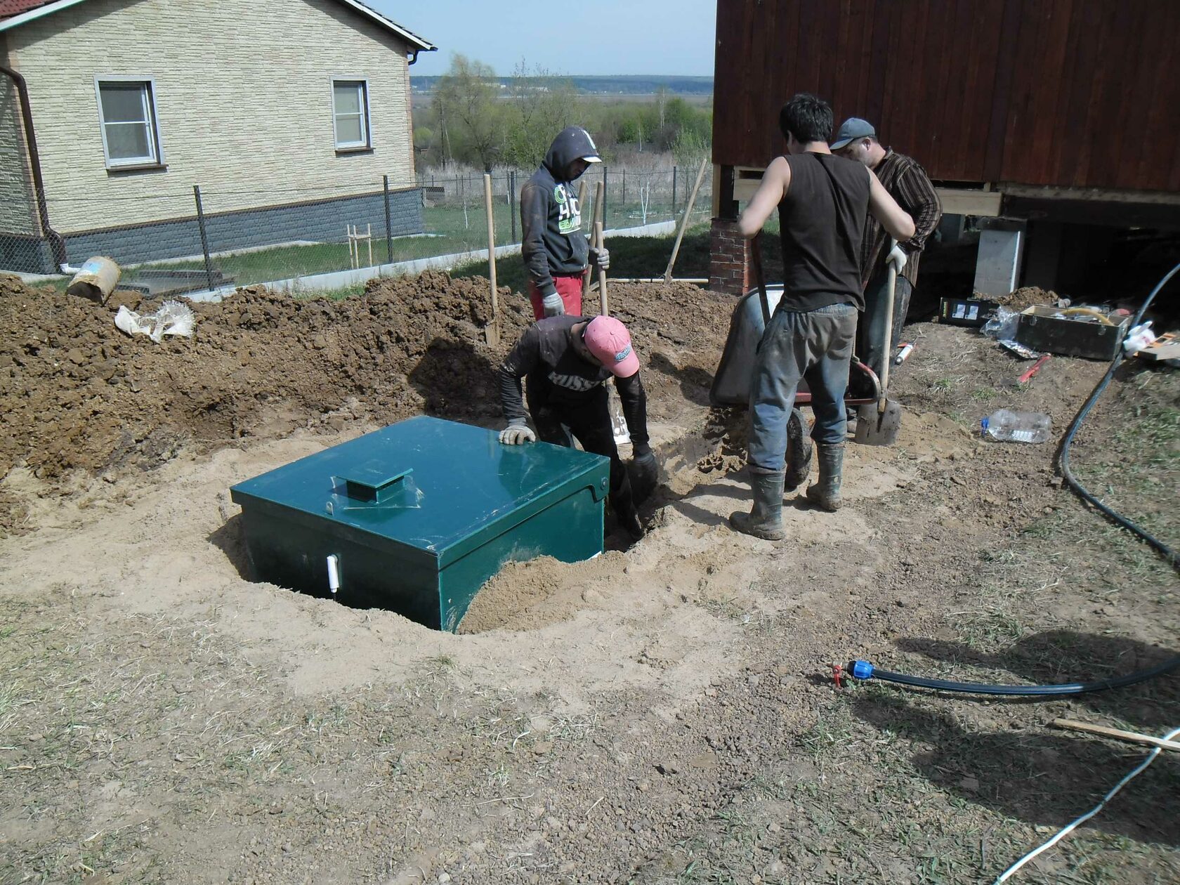 Бригада устанавливает септик возле загородного дома